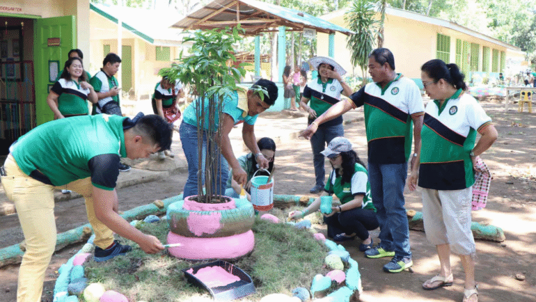 students and parents cleaning a school yard